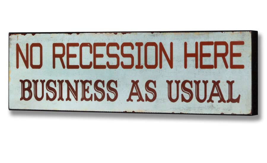 Sign stating 'NO RECESSION HERE BUSINESS AS USUAL' against a distressed background.