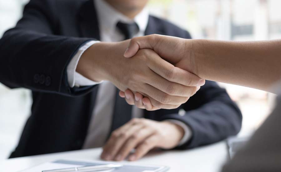 Business handshake at a desk, representing strategic hiring practices.