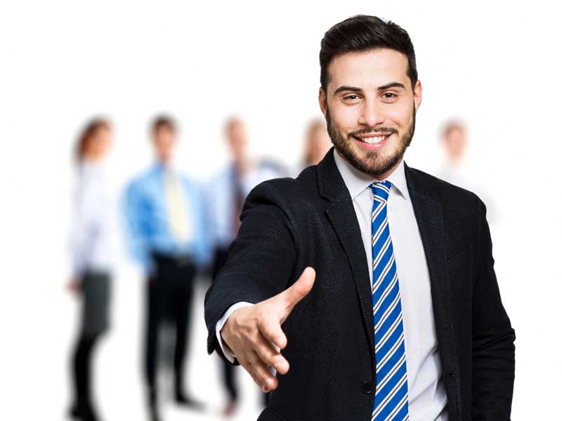 Confident businessman extending hand for a handshake in front of his team.