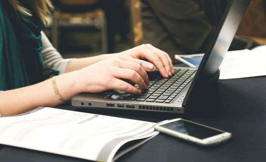 A young professional working on a laptop, focusing on job advertisements.